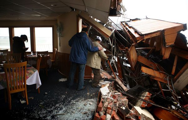 Cena Shafiee steadies his father Ali Shafiee as he tries to retrive an item from the debris in his restaurant, Alexander's on the Bay. Alexander's on the Bay, in the Chic's Beach section of Virginia Beach, has stood here for more than two decades and has withstood many storms. (Vicki Cronis-Nohe | The Virginian-Pilot)