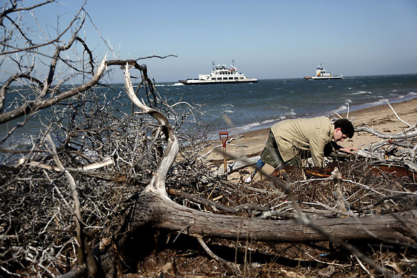 Matthew Farkas examines part of ship on Monday, Feb. 14, 2011, that he and Scott Dawson found on Hatteras Island on the Outer Banks, N.C.
