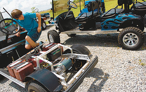 Jeffrey Durham, 14, backs up a go-cart  in order to work on a six-seater golf cart “limousine” Wednesday. His grandfather, Steve Jones, builds custom-made golf carts.   